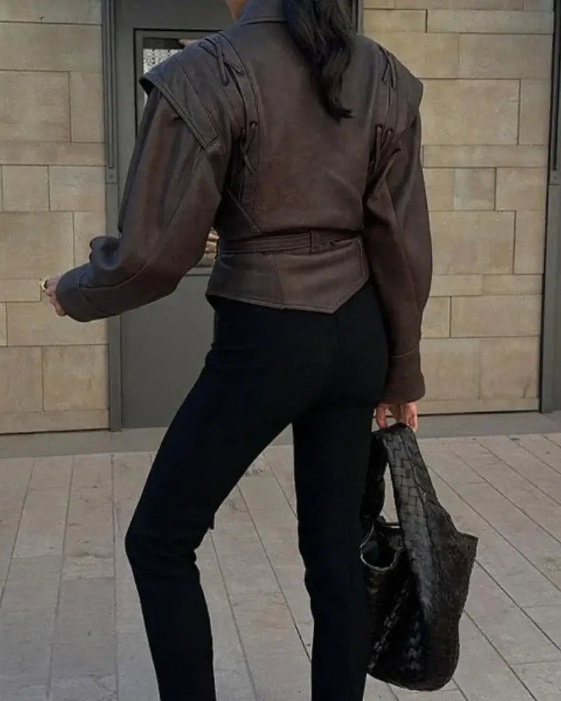 Rear view of a woman in a Liora Structured Wrap Jacket, showcasing its bold shoulder design and cinched waist.